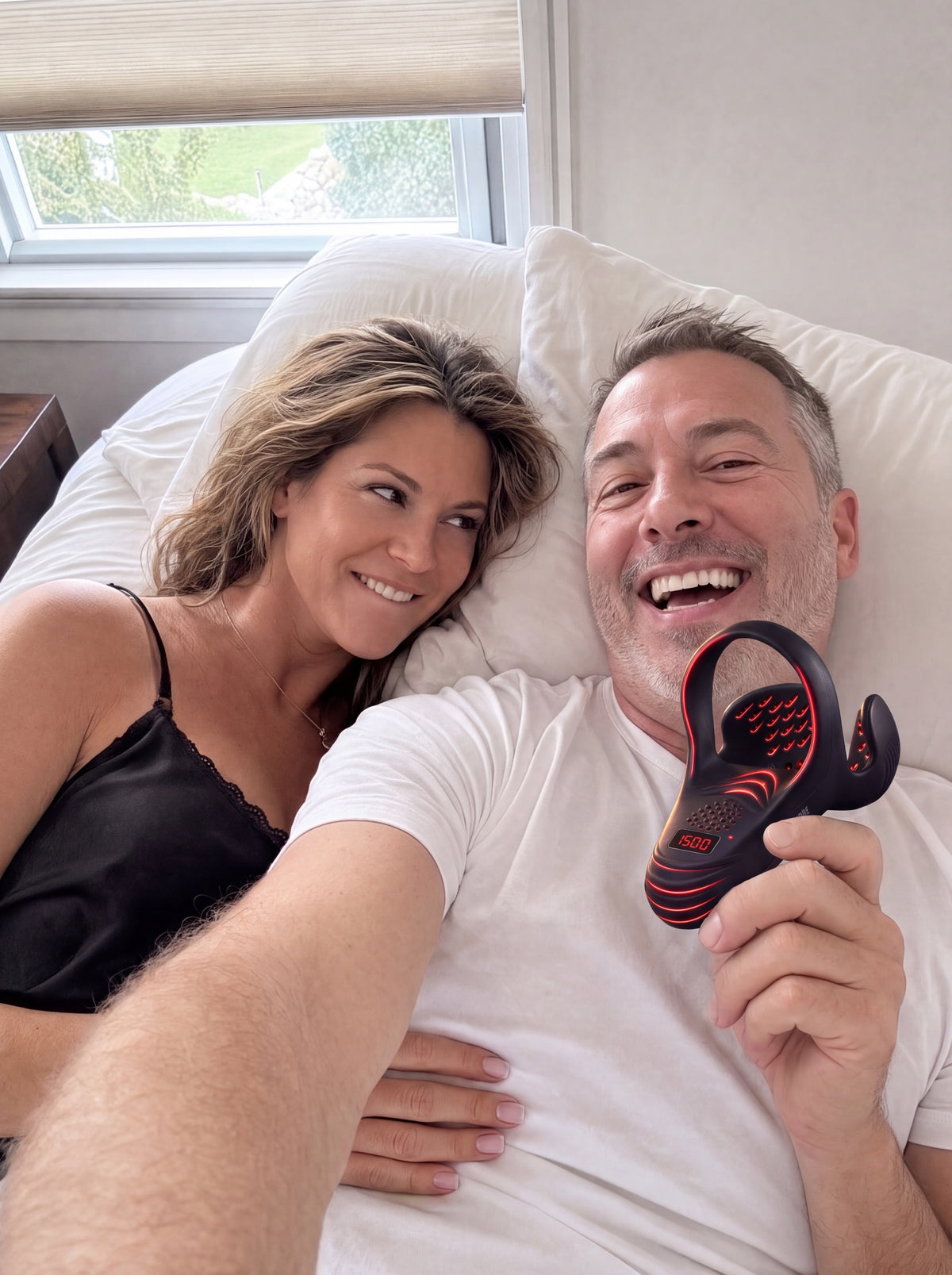 A couple in bed taking a selfie, him laughing and holding VasoCore